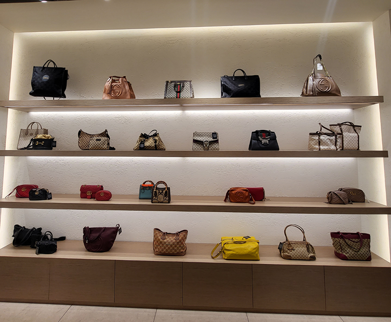 Authentication specialist inspecting a luxury handbag with a magnifying glass